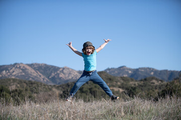 Happiness, childhood, freedom, movement and people concept. Happy smiling boy jumping on nature.