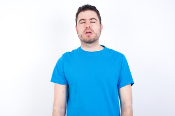 Fototapeta premium young handsome caucasian man wearing blue t-shirt against white background looking sleepy and tired, exhausted for fatigue and hangover, lazy eyes in the morning.
