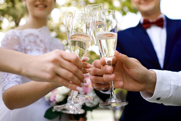 Happy newlyweds on their wedding day walk with close friends and drink champagne to celebrate