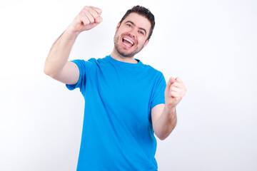 Fototapeta premium young handsome caucasian man wearing blue t-shirt against white background imagine steering wheel helm rudder passing driving exam good mood fast speed