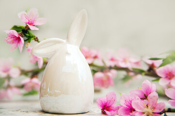 Happy easter. Easter porcelain bunny on background of blossoming branch.