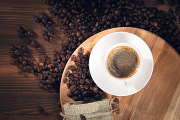 cup of coffee with coffee beans on wooden background