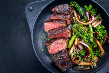 Modern style barbecue dry aged wagyu Brazilian picanha steaks from the sirloin cap of rump beef with rapini broccoli rabe and caramelized radicchio tardivo served as top view in a design skillet