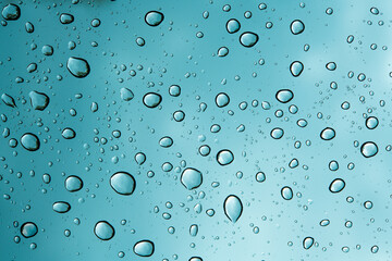 Water drops on a clear Glass. Wet surface. Rainy cloudy day. Raindrops on glass. Water splash or dew on a window. Cloudy blue sky. Super macro photo background. 