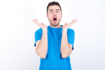 Surprised terrified young handsome caucasian man wearing blue t-sGestures with uncertainty, stares...