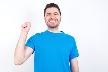 Fototapeta premium young handsome caucasian man wearing blue t-shirt against white background pointing up with fingers number ten in Chinese sign language Shi