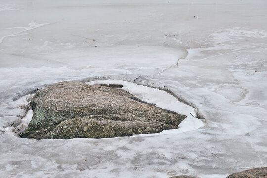 Ice around the stone on the river in early spring.