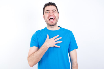 young handsome caucasian man wearing white t-shirt against white background smiles toothily cannot believe eyes expresses good emotions and surprisement