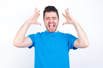 young handsome caucasian man wearing white t-shirt against white background goes crazy as head goes around feels stressed because of horrible situation