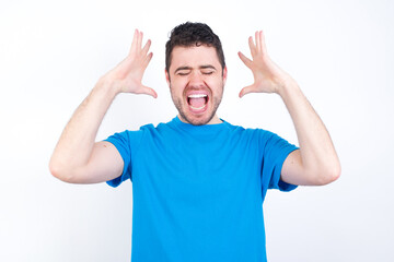 Fototapeta premium young handsome caucasian man wearing white t-shirt against white background goes crazy as head goes around feels stressed because of horrible situation