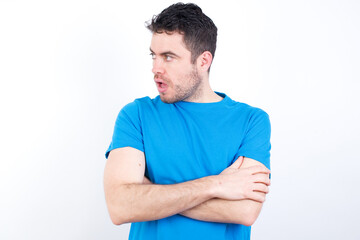 Fototapeta premium Astonished young handsome caucasian man wearing white t-shirt against white background looks aside surprisingly with opened mouth.