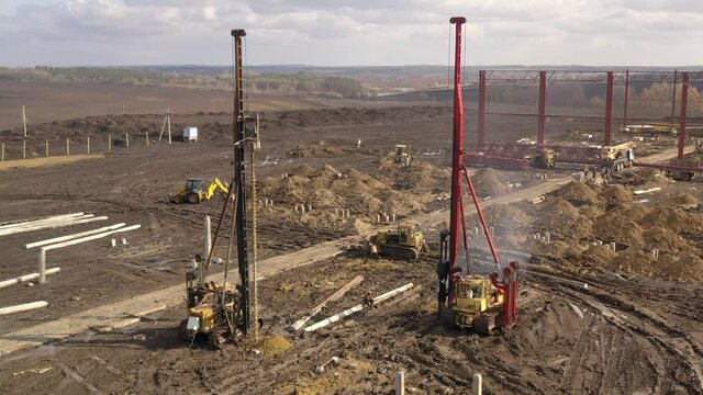 Excavation at a construction site, diesel pile driving machine with rumble and smoke drives piles deep into the ground to ensure the strength of the foundation of the future structure