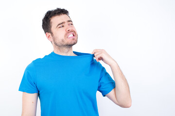young handsome caucasian man wearing white t-shirt against white background stressed, anxious, tired and frustrated, pulling shirt neck, looking frustrated with problem