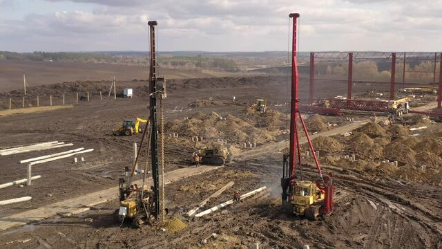 Excavation at a construction site, diesel pile driving machine with rumble and smoke drives piles deep into the ground to ensure the strength of the foundation of the future structure
