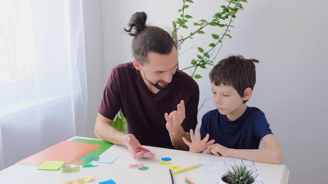 Autistic boy during therapy at home with his father with school therapist learning and having fun together. Autism awareness concept. 4K, slow motion
