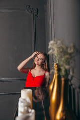 beautiful girl in a red dress stands against a dark wall