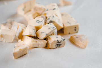 Mix of cheeses on plate. Slicing blue cheese dorblu, gorgonzola, roquefort. French gourmet traditional cuisine.