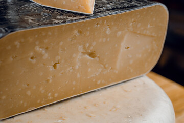 Goat cheese wheel and big pieces of it. Mix of cheeses from goat milk.