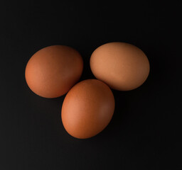 Chicken eggs with brown shell on black background