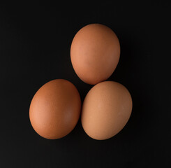 Chicken eggs with brown shell on black background