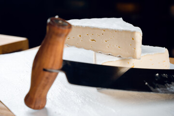 Fototapeta premium Brie soft white cheese from cow milk. Slicing brie on the wooden table. Organic delicious food