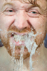 Whte man under shower water streams, dynamic face with beard