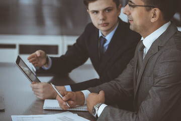 Businessman headshot at meeting in modern office. Entrepreneur sitting at the table with colleagues. Teamwork and partnership concept. Grey blazer suits to happy smiling manager