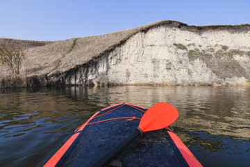 Paddling in red packraft rubber boat on the river at spring. Selective focus. Active lifestile...