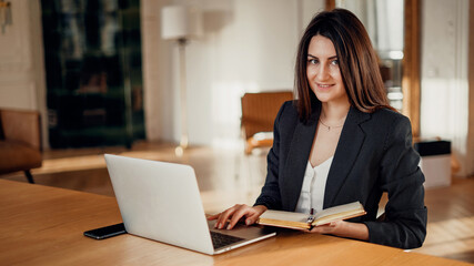 A businesslike young woman of American appearance. Online foreign language training. Comfortable working space in a coworking space. The manager works on a tablet computer in the office.
