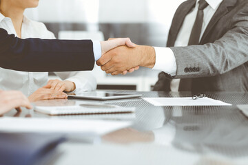 Handshake as successful negotiation ending, close-up. Unknown business people shaking hands after contract signing in modern office