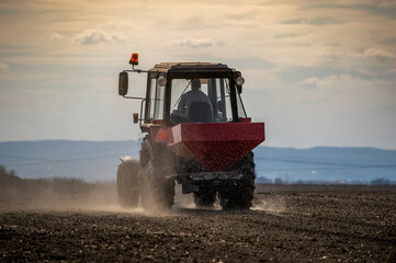 Fototapeta premium Tractor spreading artificial fertilizers