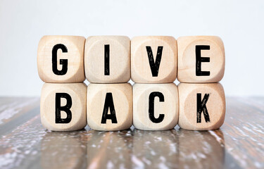 Give Back word written on wood block. Give Back text on table, concept.
