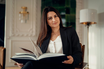 Obraz premium A businesswoman is in a modern, stylish office. Clothing business suit in black. A satisfied finance manager.