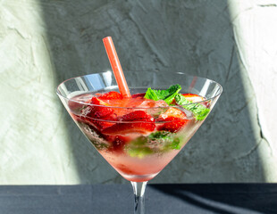  cooling strawberry cocktail with ice and mint on black and concrete background, stylish and tasty, unusual martini
