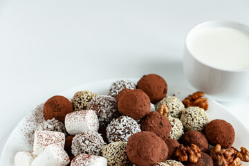 truffles with cocoa, coconut and sesame with chocolate and marshmallows and a cup of fresh milk, delicious dessert