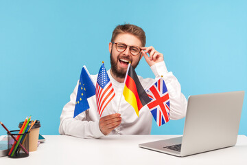 Smiling man teacher adjusting eyeglasses holding flags of usa, german, great britain and europe...