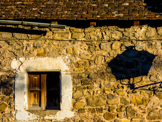 La sombra de un farol se proyecta sobre una fachada de piedra cerca de una ventana enmarcada con cal al atardecer en una aldea de montaña de los Pirineos españoles