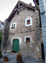Fachada de piedra, puerta verde y ventanas con molduras encaladas en la aldea de montaña de Hechó, en los Pirineos españoles