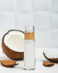 Glass bottle with coconut oil and half a coconut on a white background. Cosmetic coke oil. Health and beauty concept.