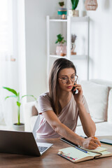 Young woman using mobile phone and laptop to work home, remote work