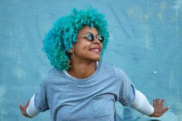 black afro american woman smiling with sunglasses outdoors on background wall