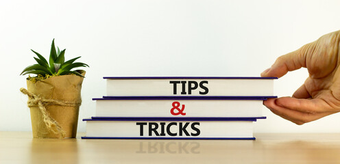 Tips and tricks symbol. Books with words 'Tips and tricks'. Businessman hand, house plant....