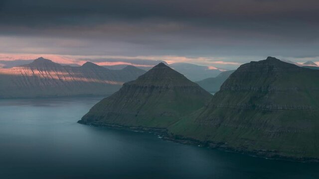 Time lapse of sunset in the fjord at viewpoint Hvithamar with moving clouds over island Kalsoy, Funningur Gjogv Faroe Islands
