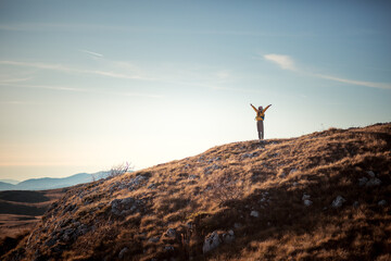 Successful woman raising hands on mountain