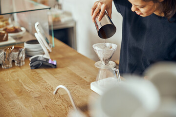 Barista female is making delicious, freshly ground morning coffee powder in the coffee filter