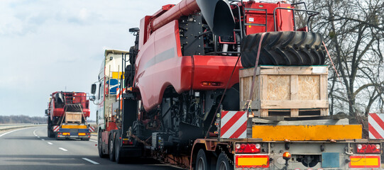 Many heavy industrial truck with semi trailer platform transport disassembled combine harvester...