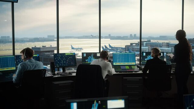 Diverse Air Traffic Control Team Working in a Modern Airport Tower. Office Room is Full of Desktop Computer Displays with Navigation Screens, Airplane Departure and Arrival Data for Controllers.