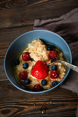 Oatmeal with berries on a wooden background. Useful healthy breakfast.