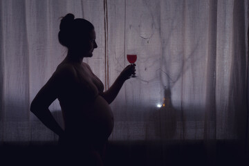 Adult pregnant woman with a glass of wine, shadow. Problems with alcohol during pregnancy,...
