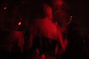 People dancing and celebrating in a nightclub, shot in red light on long exposure.